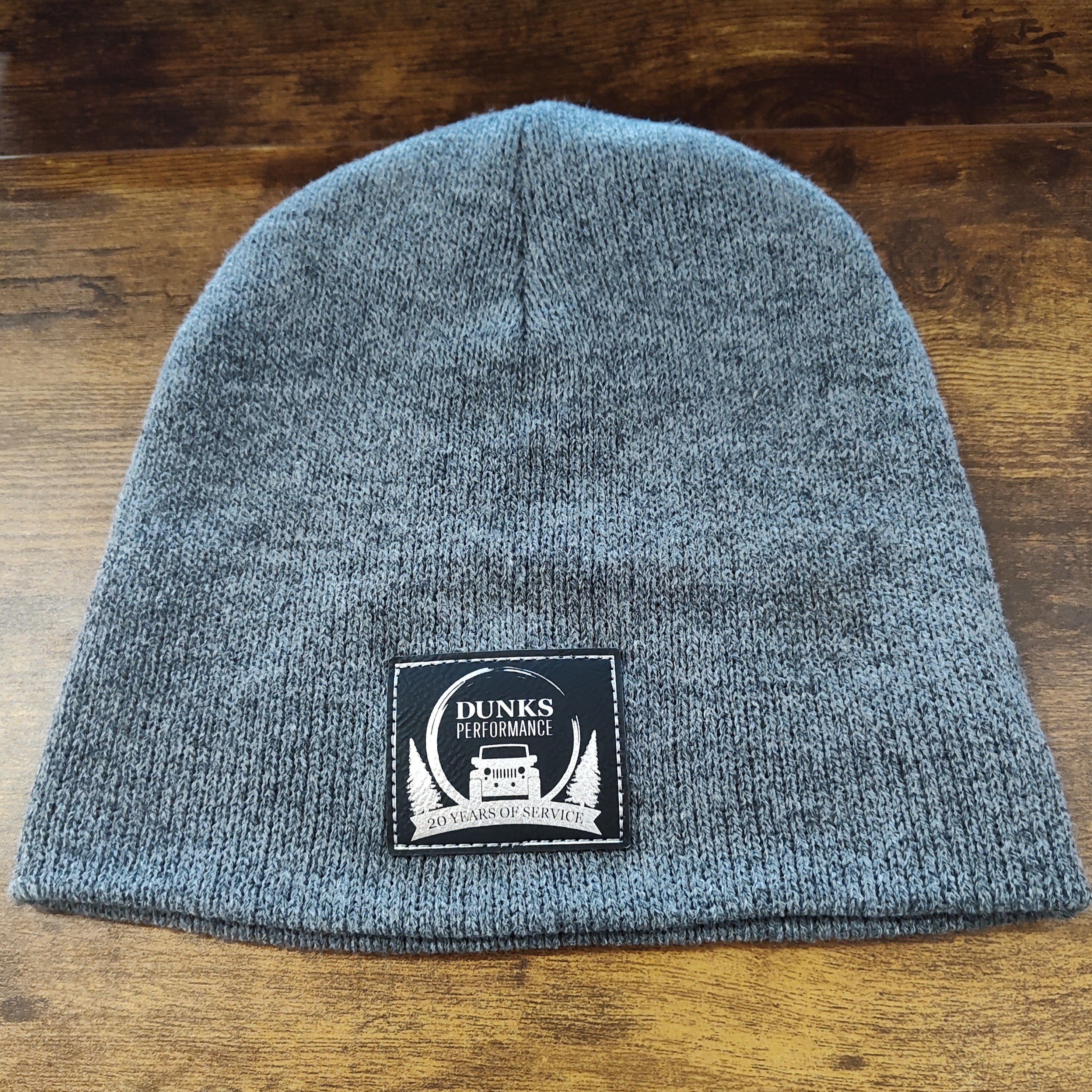 Gray knit beanie with a patch on a wooden surface