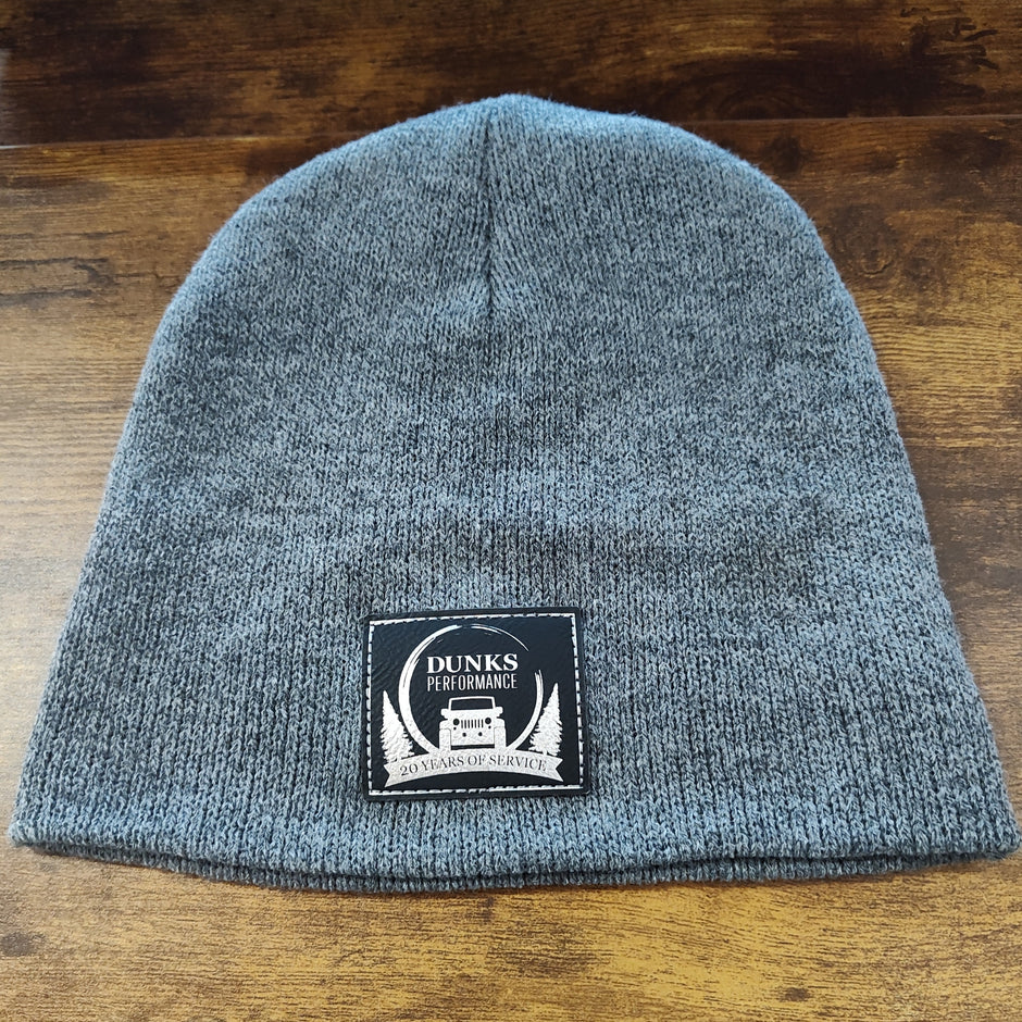 Gray knit beanie with a patch on a wooden surface