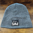 Gray knit beanie with a patch on a wooden surface