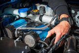 Mechanic installing the compact ARB CKBLTA12 brushless air compressor into a vehicle.