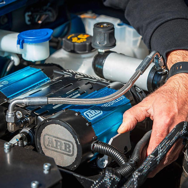Mechanic installing the compact ARB CKBLTA12 brushless air compressor into a vehicle.