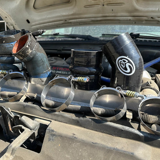 S&B hot side intercooler boots and T-bolt clamps resting on the engine bay of a Ford 6.0L Powerstroke